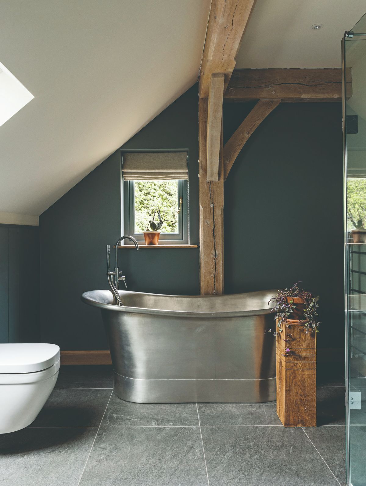A freestanding metal bath tub on a flagstone floor