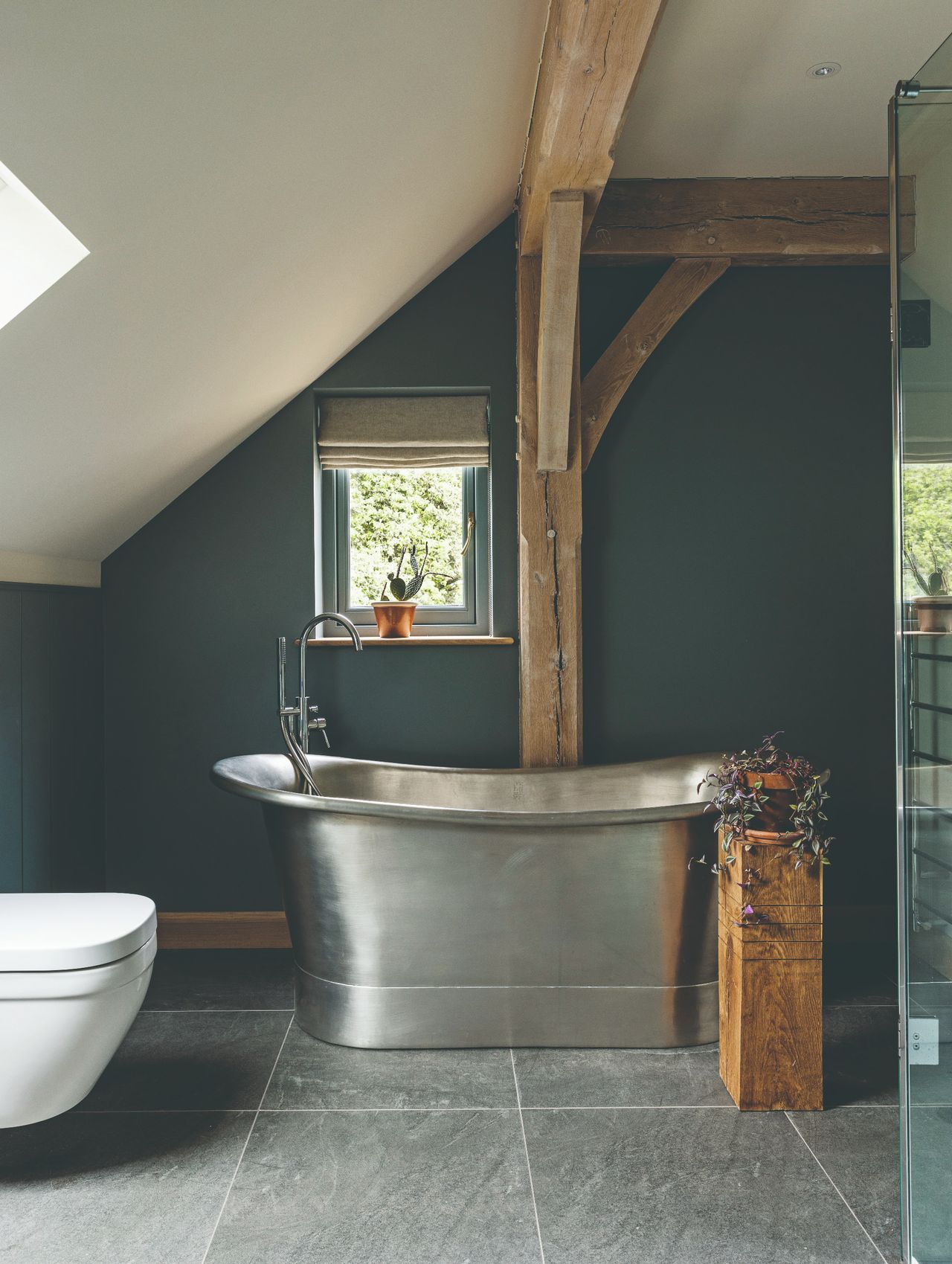 A freestanding metal bath tub on a flagstone floor