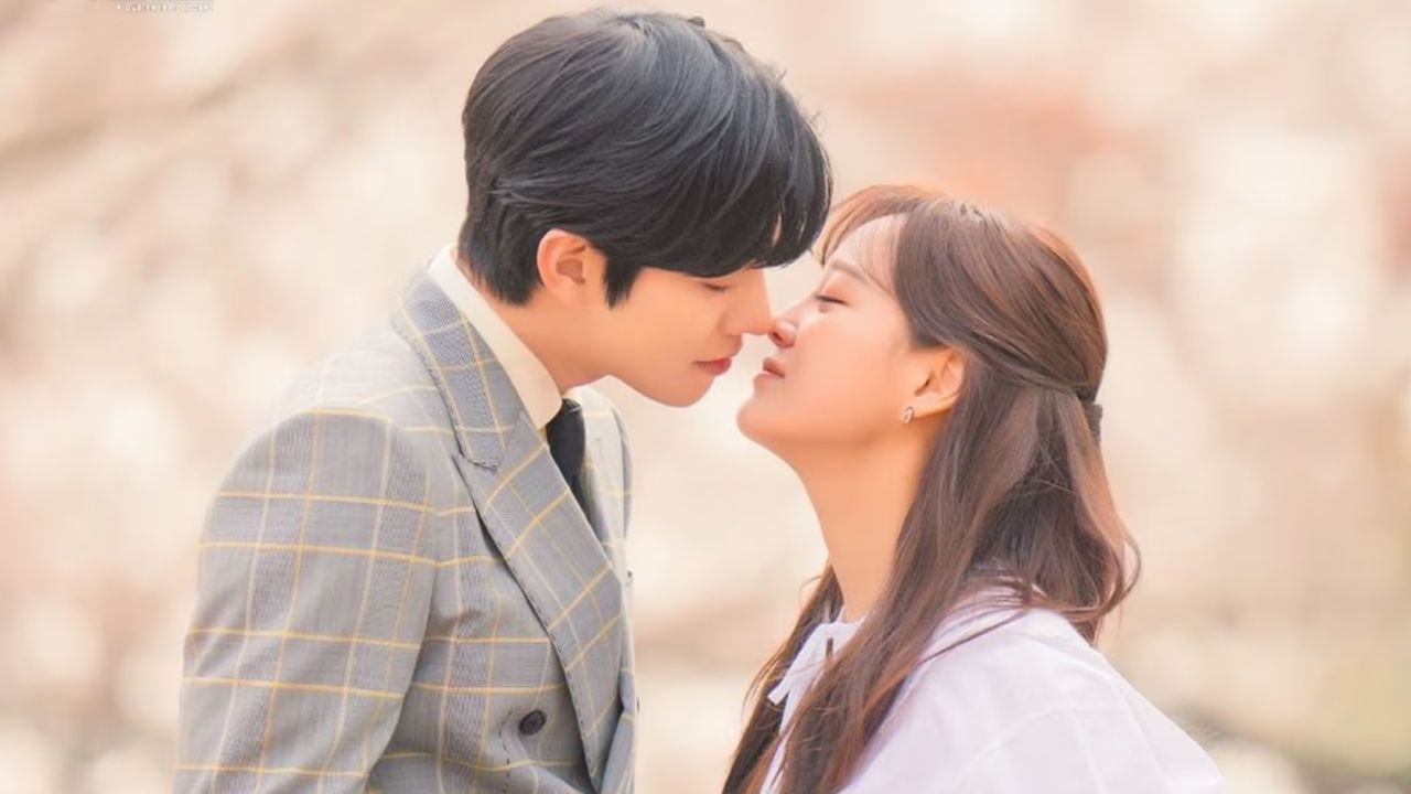 a man in a plaid suit and a woman in a purple top lean in for a kiss in a still from the k-drama business proposal