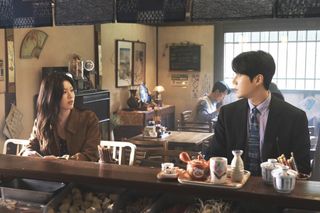 A woman (Go Youn-jung) and a man (Kim Seon-ho) look at each other while sitting at the bar in a restaurant, in 'Can This Love Be Translated?'