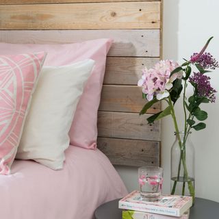wooden headboard with glass flower vase and water glass