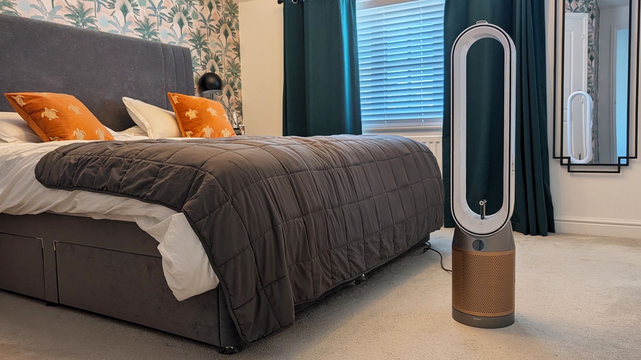 The Dyson Find+Follow Purifier Cool standing in someone's bedroom.