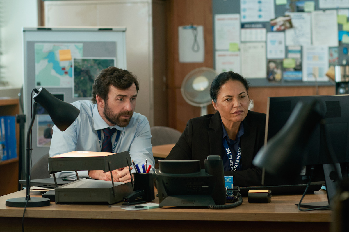 a male and female detective sititng at a desk investigating in the survivors netflix
