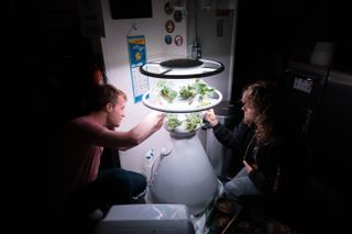 Officers Sean Gellenbeck and Brandy Nunez attending the HI-SEAS LettuceGrow hydroponic greenhouse tree.