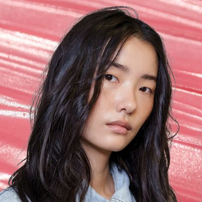 Two models with luminous, highlighted skin, staring at the camera. There is a pink background behind them. 