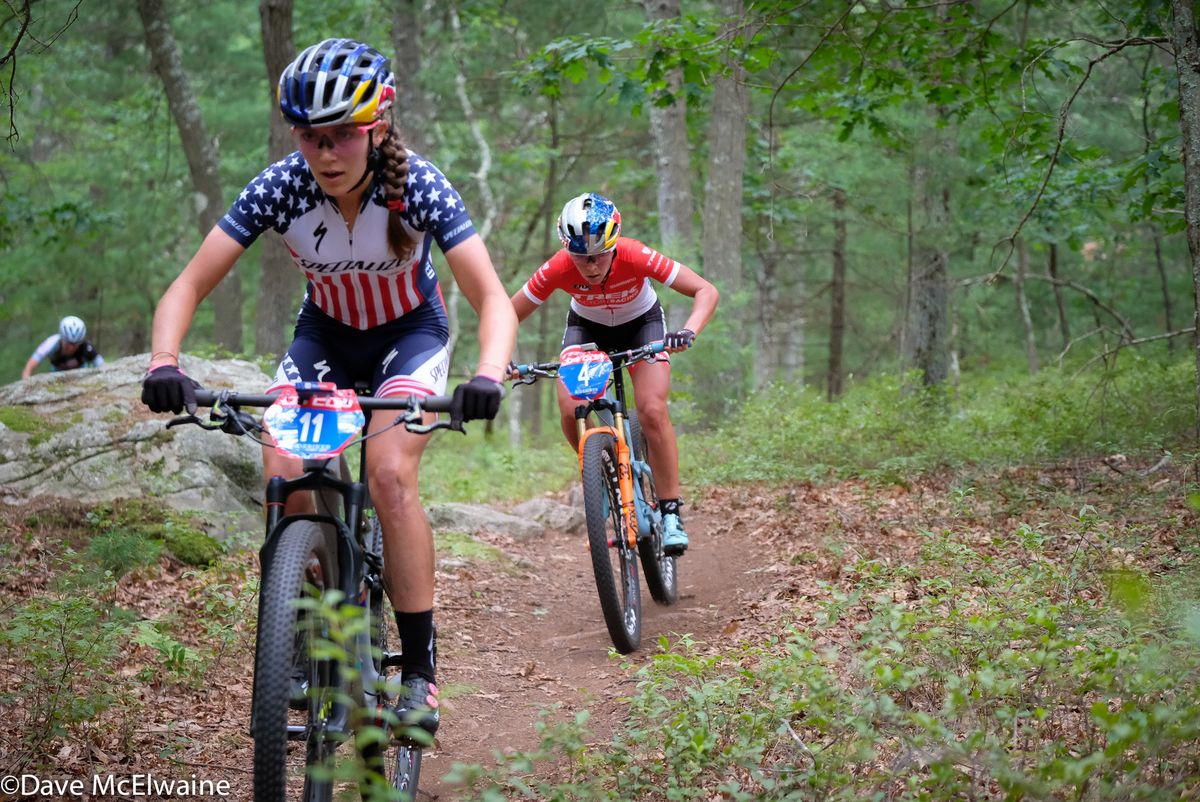 Kate Courtney (Specialized) and Emily Batty riding in thick forest with Rose Grant chasing