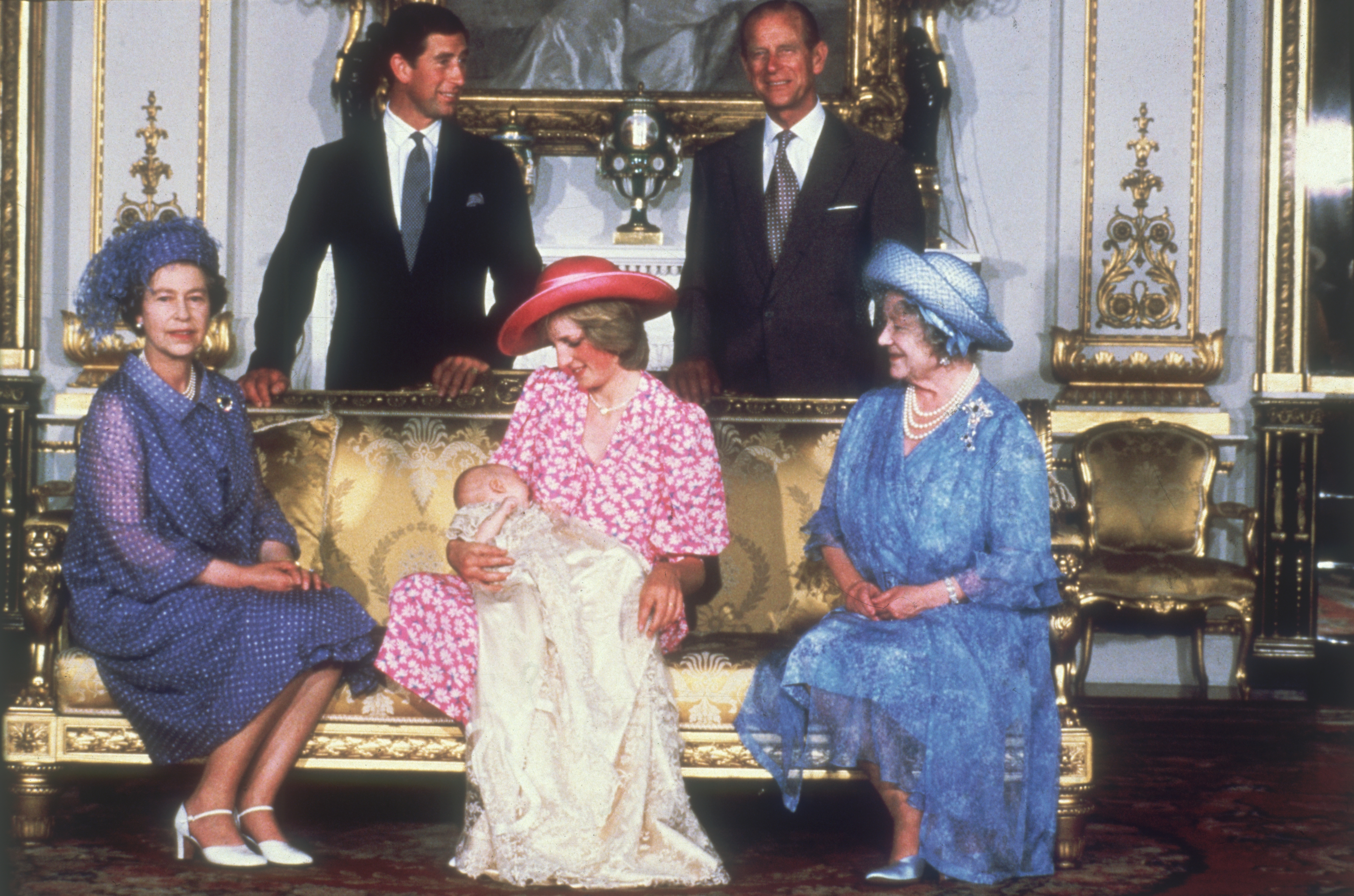 Queen Elizabeth II wears a pink coat and holds a black umbrella leaving the Lindo Wing after Prince William's birth, and the Royal Family poses for photos at William's christening