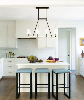 A white kitchen with blue bar stools