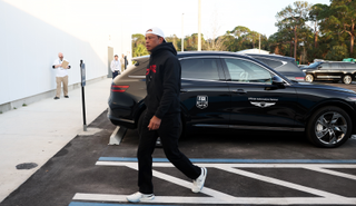 Tiger Woods walks past a car