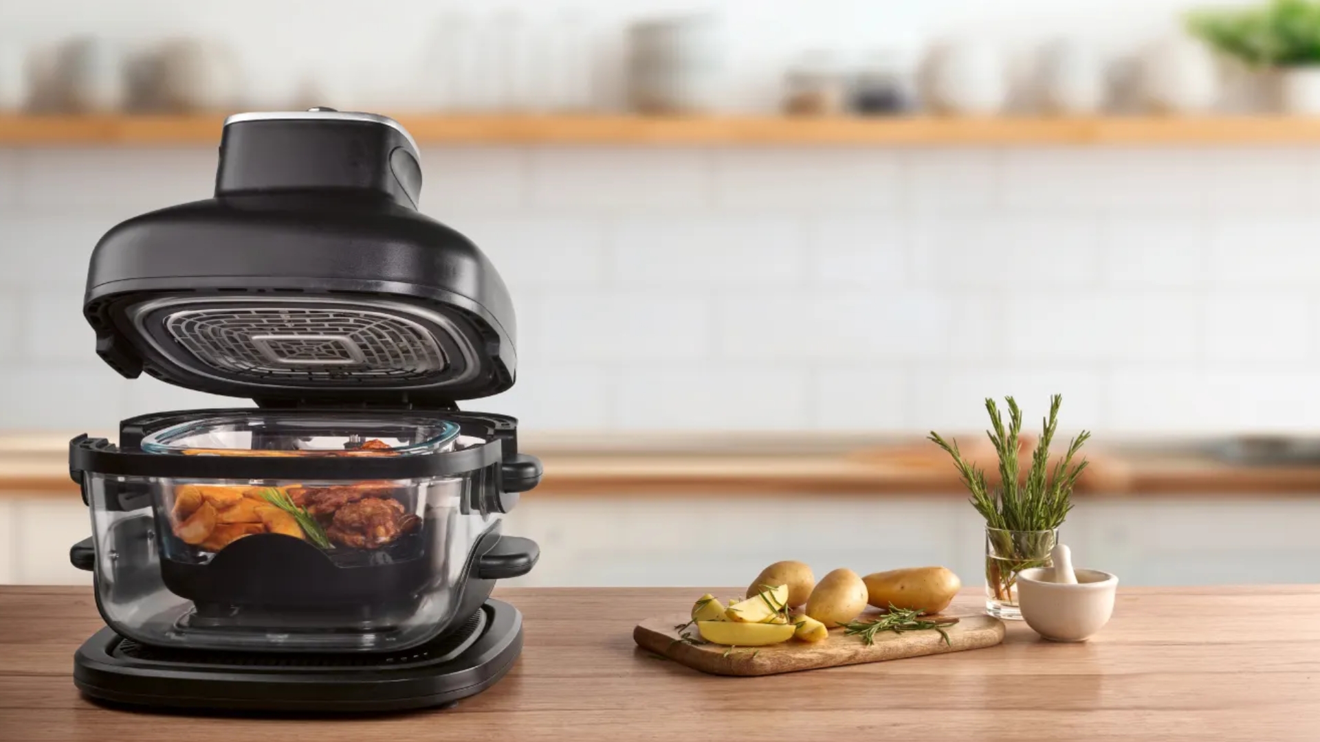 Lidl SilverCrest Glass Air Fryer on a wooden counter with chips and herbs beside it