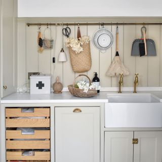 Laundry room with sink, neutral cabinets and wall-mounted cleaning supplies