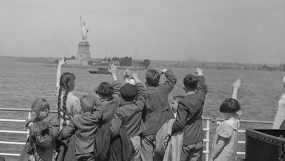 Young Austrian immigrants fleeing Nazi persecution wave to the Statue of Liberty upon their arrival in the US