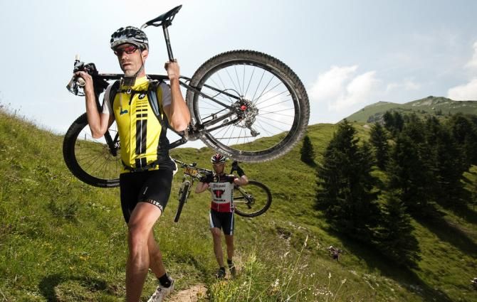 A rider hikes his bike during stage 6