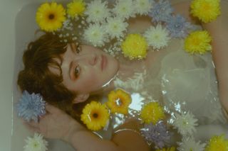 Photo of a girl in a bath surrounded by yellow and white flowers