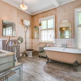 pink bathroom with wooden floor and bathtub