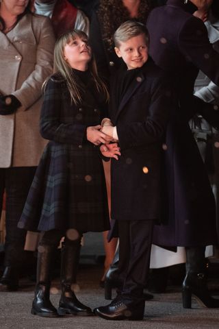 Princess Gabriella and Prince Jacques wearing dark coats holding hands outside