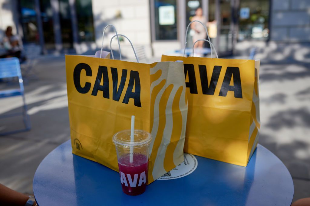 Yellow Cava to-go bags sitting on blue table outside of restaurant in Brooklyn, New York