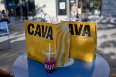 Yellow Cava to-go bags sitting on blue table outside of restaurant in Brooklyn, New York