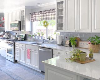 Modern country kitchen with potted herbs and plants, and short check curtain detail.