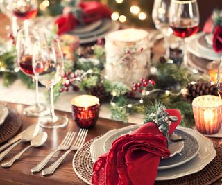 Christmas tablescape with plates and red napkins decorated on either side of a Christmas tablerunner