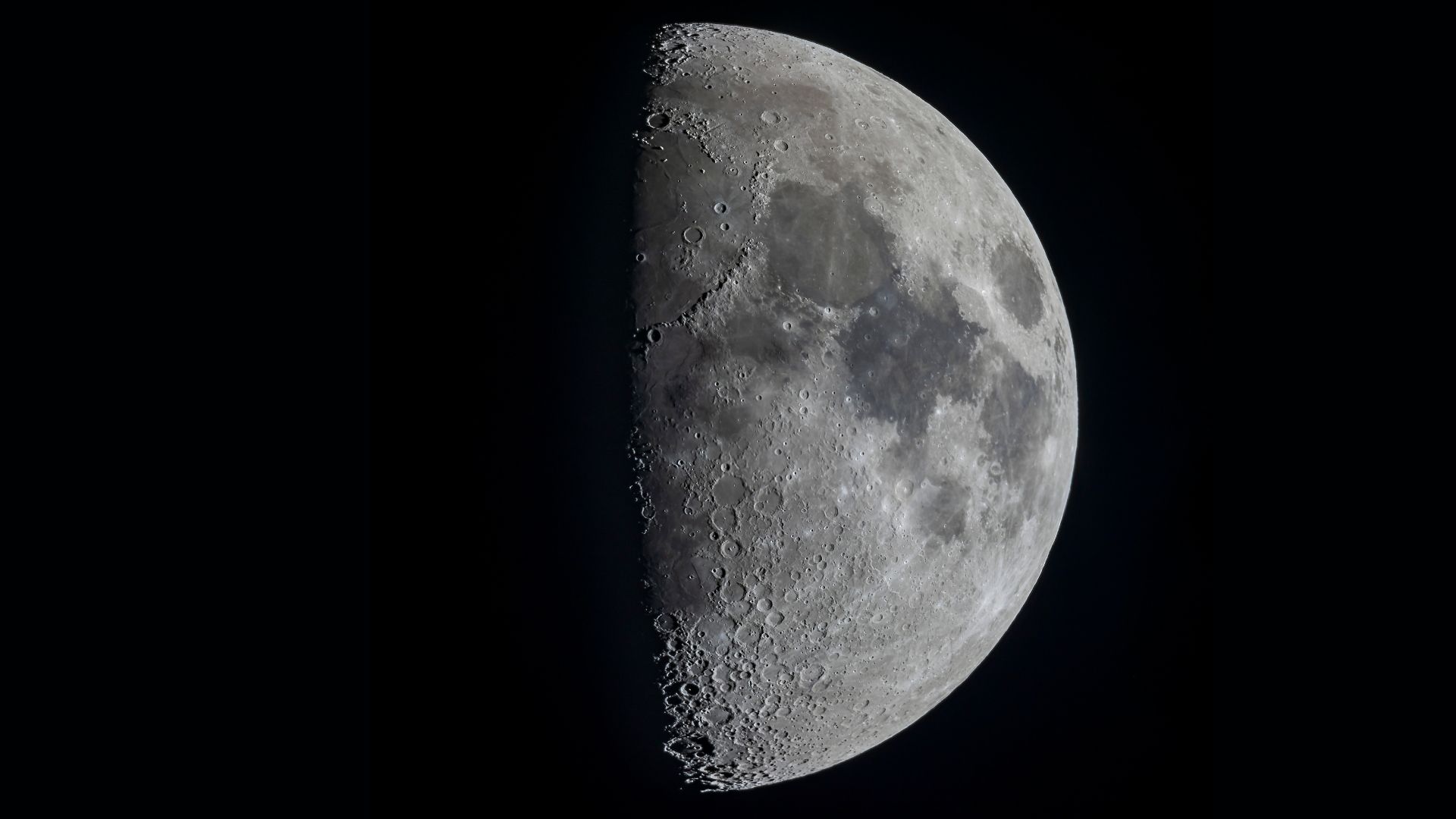 A half lit moon is shown in a black sky