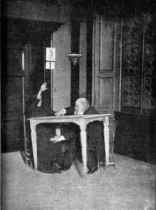 Eusapia Palladino who, in an 1892 photograph taken in Milan, and shown here, supposedly levitated a table while researcher Alexandr Aksakov checked for fraud.
