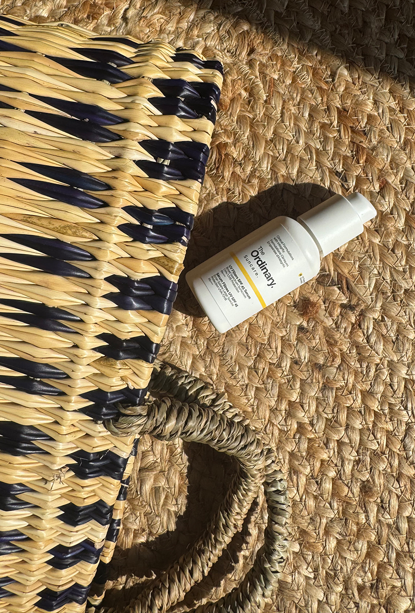 The Ordinary SPF serum with beach bag and textured jute background