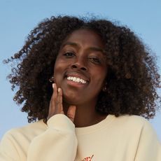 woman smiling and touching her face