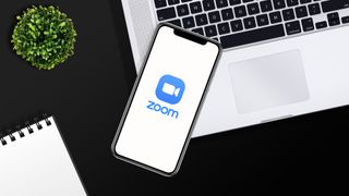Zoom logo on phone screen on cluttered desk