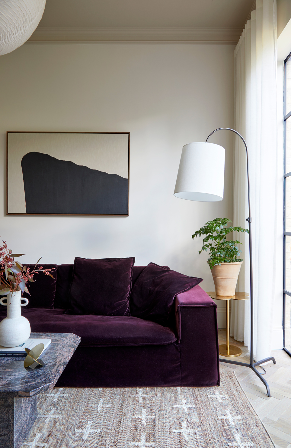 Image of a purple sofa in a white living room with neutral decor accents.