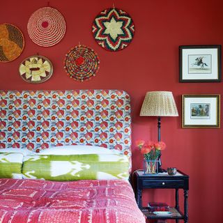 Red bedroom with woven wall baskets and a patterned fabric headboard