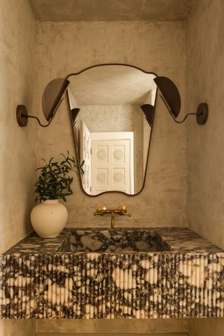 A powder bathroom with a limewash wall behind the sink