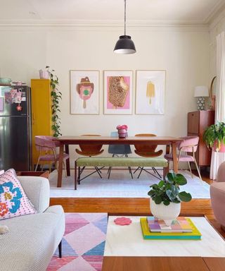 A dining room with a brown table, wall art, and pink seats