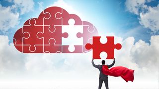 A businessman wearing a red superhero cape lifting the final piece of a puzzle in the shape of a cloud into place