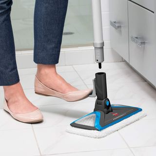 Woman stepping down on Bissell SlimSteam floorhead to attach tube