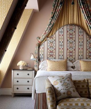 Traditional bedroom with bed with high patterned headboard, canopy, sloped ceiling