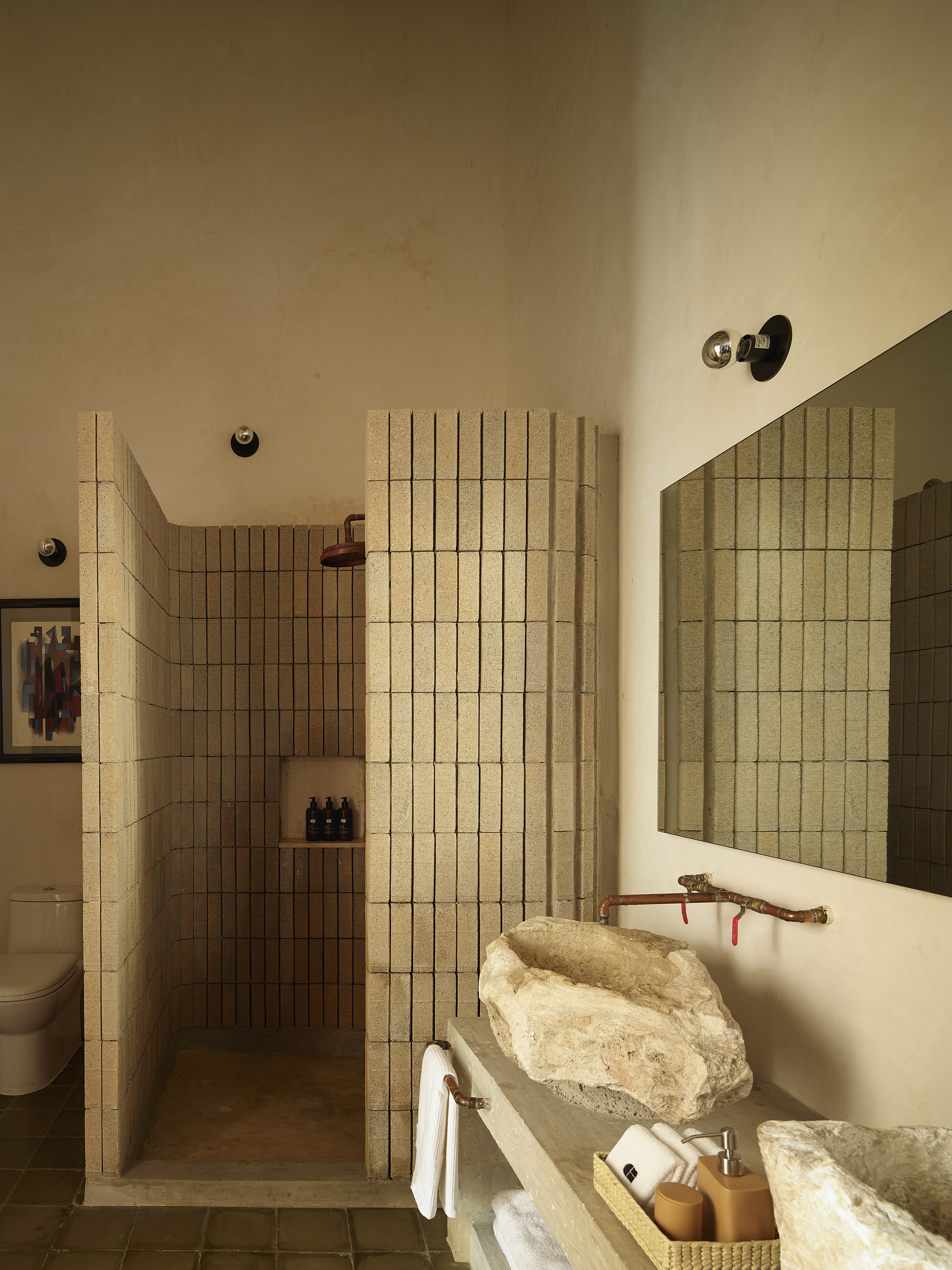 A bathroom with a shower niche made of small concrete tiles