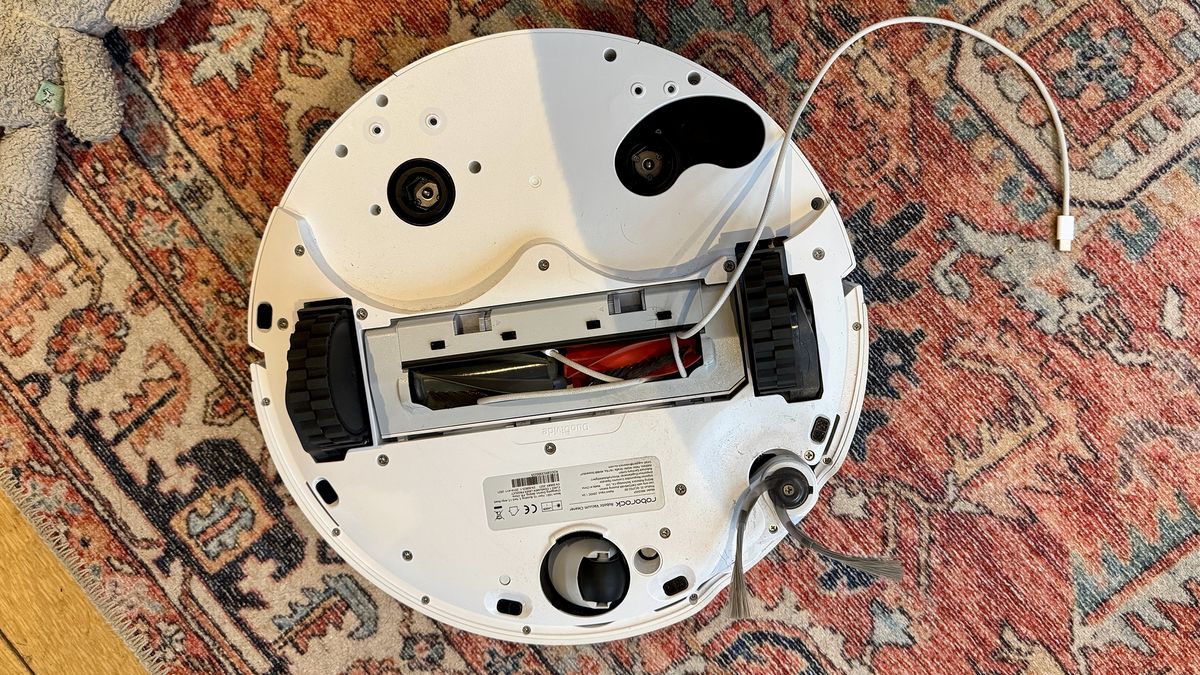 Roborock Qrevo Curv 2 Pro avoiding obstacles including a wire and dog toys, on a patterned rug