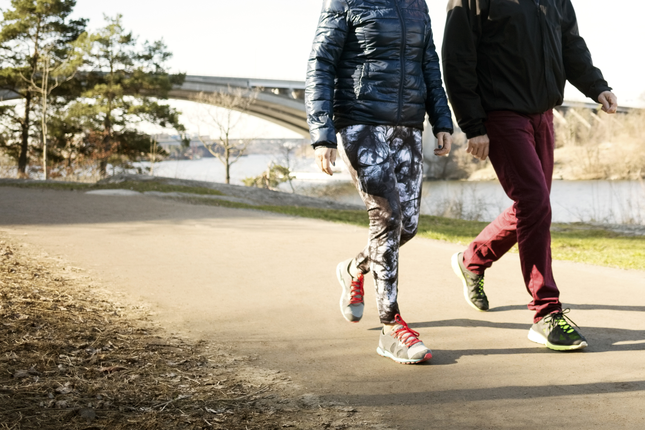 Low section of man and woman in sportswear walking on road - stock photo