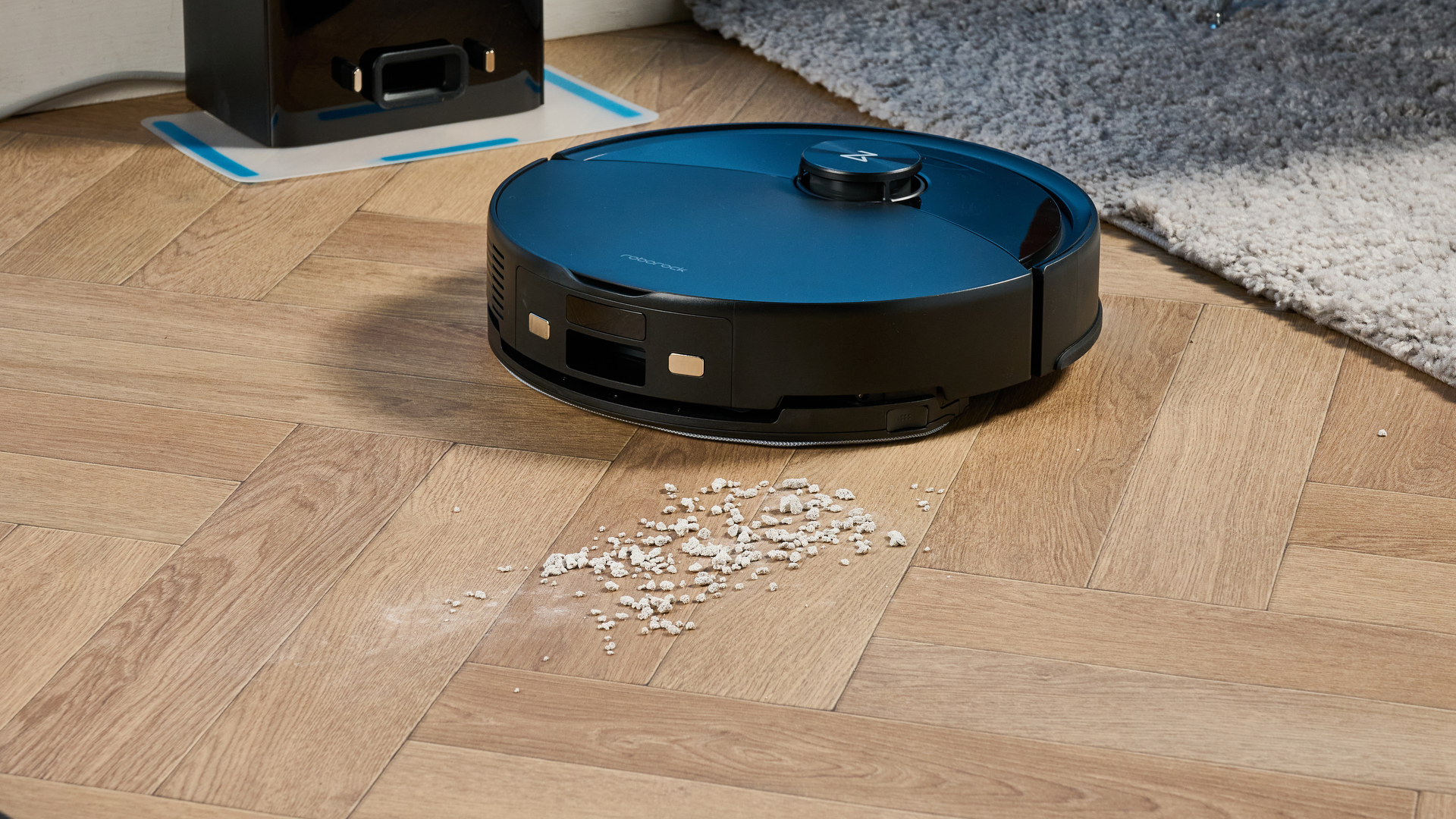 Roborock Q10 S5+ photographed on a wooden floor in front of a blue background