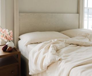 Cozy Earth bedding on a bed beside a nightstand against a white wall.