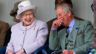 Queen Elizabeth II and Prince Charles, Prince of Wales laugh whilst watching the children's sack race