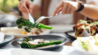 foods rich in vitamin c - woman picking up tenderstem broccoli with fork