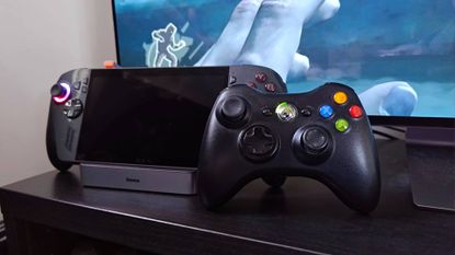 Black Xbox 360 controller leaning against ROG Xbox Ally X on Baseus Steam Deck dock.