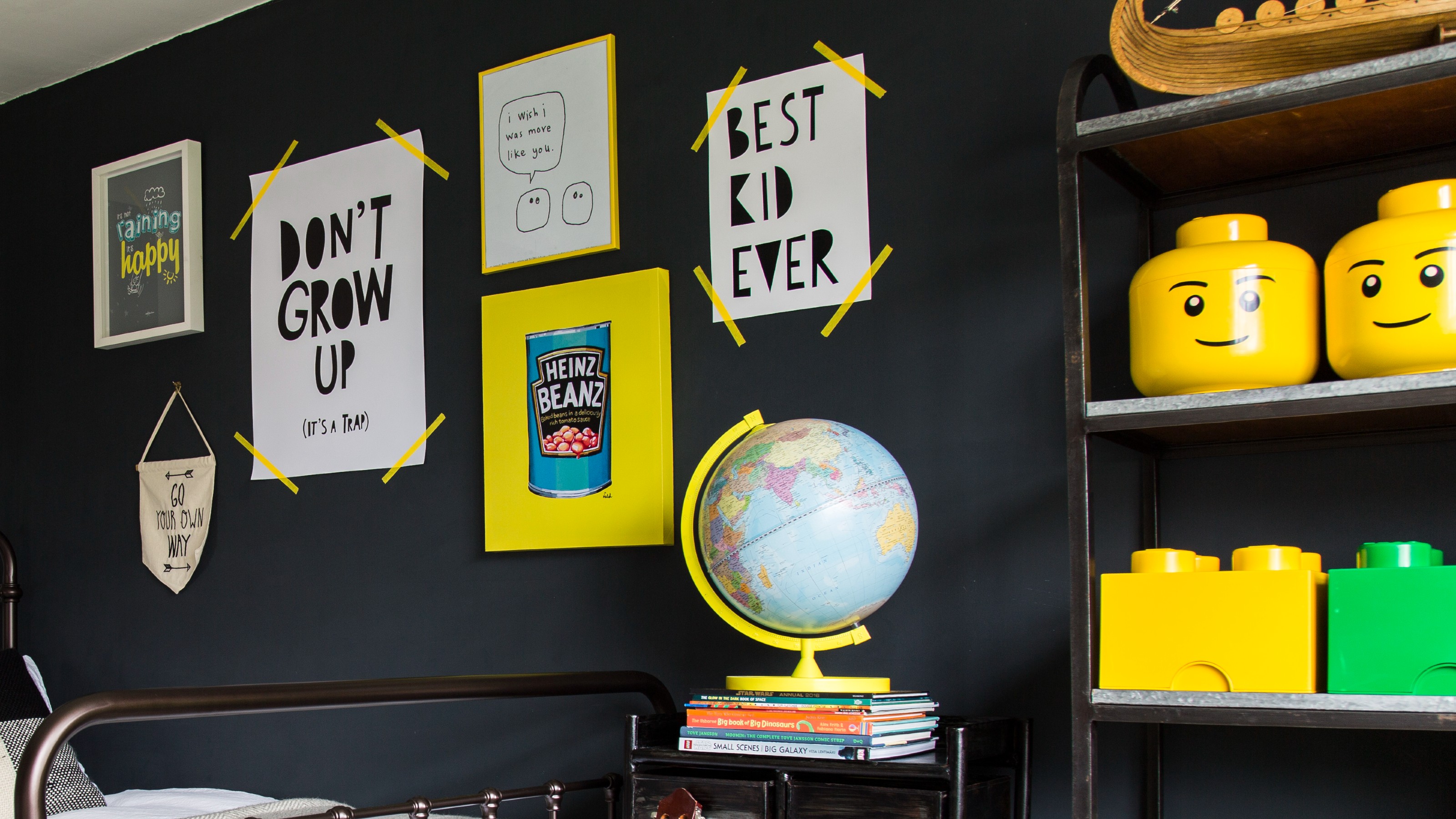 A black-painted teenager's bedroom with a Lego display and a gallery wall above the bed
