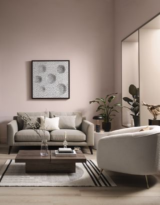 beige and blush living room with beige sofa, boucle armchair, plants, artwork, wooden coffee table, rug, wood floor