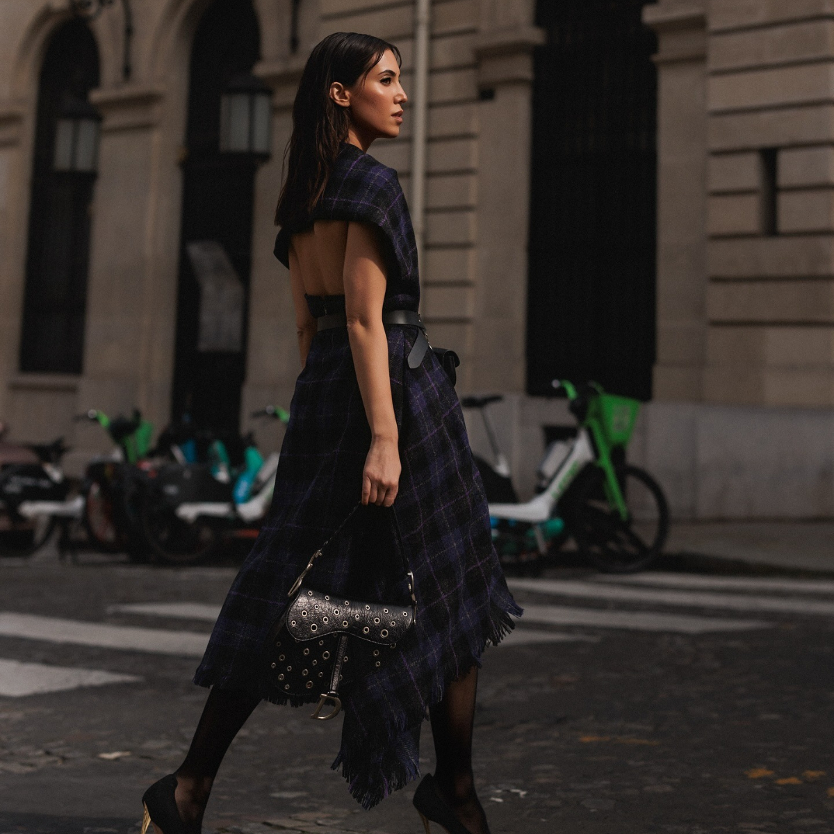 A woman in a plaid dress crossing the street in New York.