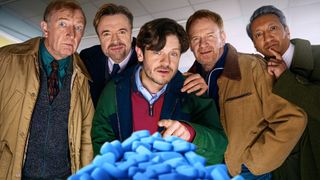 The cast BBC drama Men Up crowd around a pile of blue Viagra-style pills 