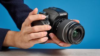 Pentax KF DSLR camera photographed on a blue background