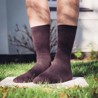 A pair of winter cycling socks stood on a tile in a garden